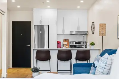 a kitchen with three chairs and a counter with a refrigerator at Luxurious DownTown Suite in Montréal