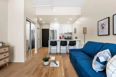 a living room with a blue couch and a kitchen at Luxurious DownTown Suite in Montréal