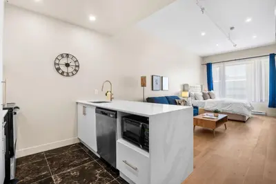 a kitchen and living room with a couch and a clock at Luxurious DownTown Suite in Montréal