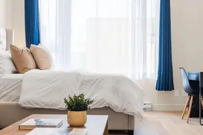 a bedroom with a white bed with blue curtains at Luxurious DownTown Suite in Montréal