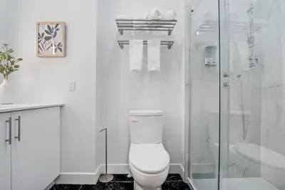 a white bathroom with a toilet and a shower at City Center King Loft in Montréal