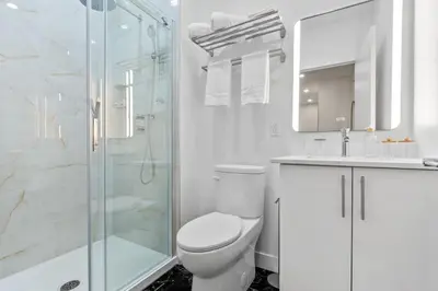 a white bathroom with a toilet and a shower at City Center King Suite in Montréal