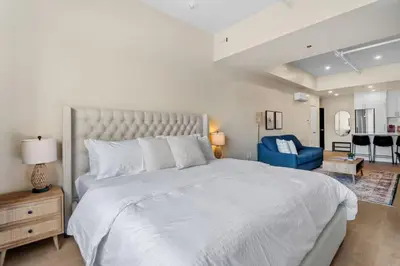 a bedroom with a large white bed and a blue chair at Luxe DownTown King Suite in Montréal