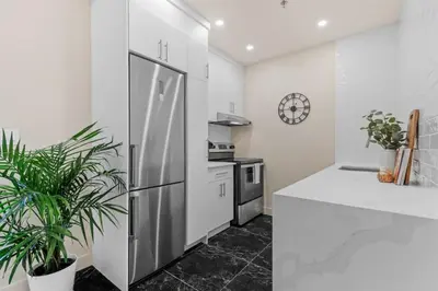 a kitchen with a stainless steel refrigerator and a clock at Downtown 2BR Suite in Montréal