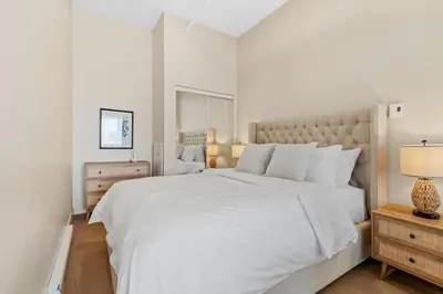 a white bedroom with a large bed and a lamp at Downtown 2BR Suite in Montréal