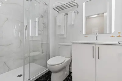 a white bathroom with a toilet and a shower at Downtown 2BR condo in Montréal