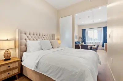 a bedroom with a large white bed and a desk at City Center 2BR Condo in Montréal