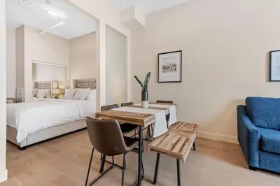 a bedroom with a bed and a table and a blue chair at City Center 2BR Condo in Montréal
