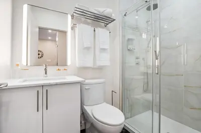 a white bathroom with a toilet and a shower at Central Studio in Montréal