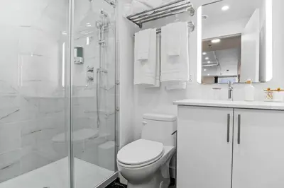 a white bathroom with a toilet and a shower at Central Suite with Balcony in Montréal