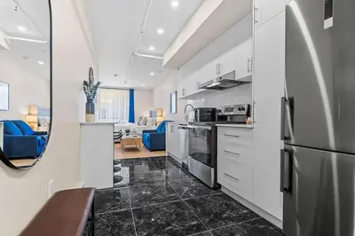 a kitchen with white cabinets and a blue couch at Central Suite with Balcony in Montréal
