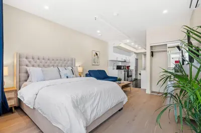 a bedroom with a large bed and a blue chair at Central Suite with Balcony in Montréal