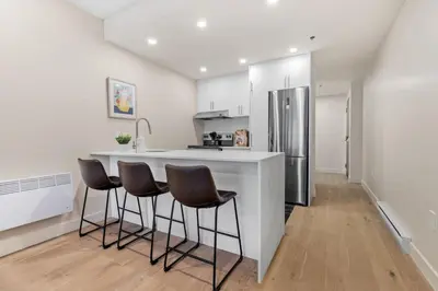 a kitchen with a white counter and stools in it at Luxurious King Suite with Balcony in Montréal