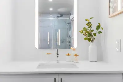 a white kitchen with a sink and a mirror at Luxurious King Suite with Balcony in Montréal