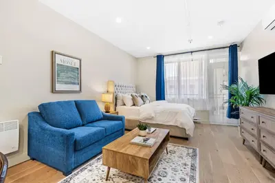 a living room with a blue couch and a bed at DownTown Studio with Balcony in Montréal