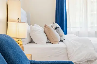 a white bed with pillows and a blue curtain at DownTown Studio with Balcony in Montréal