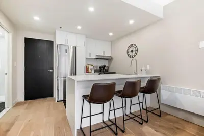 a kitchen with white cabinets and a counter with stools at DownTown Studio with Balcony in Montréal