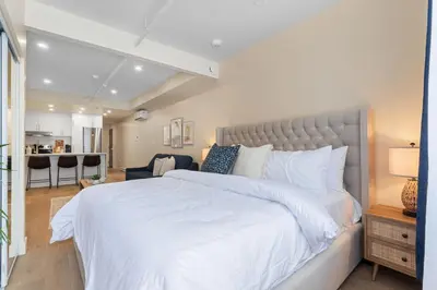 a bedroom with a large white bed and a kitchen at DownTown King Suite with Balcony in Montréal