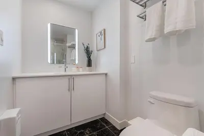 a white bathroom with a sink and a toilet at DownTown King Suite with Balcony in Montréal