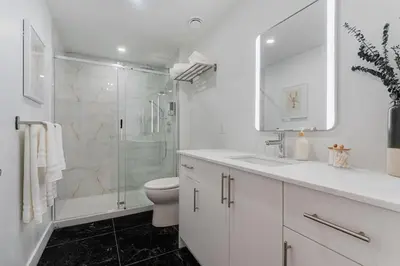a white bathroom with a shower and a toilet at 2BR Downtown Suite with Balcony in Montréal