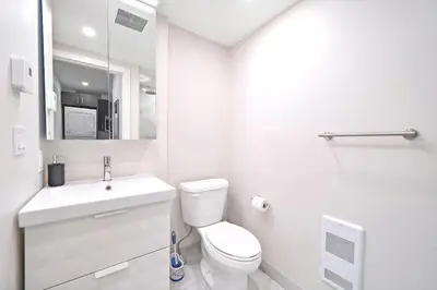 a white bathroom with a toilet and a sink at Cozy 3BDR in heart of plateau Montreal D in Montréal