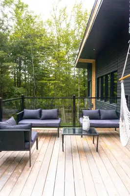 a deck with couches and a hammock on a house at Pur Nature et Spa Owl's Head in Mansonville