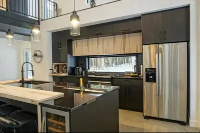 a kitchen with a stainless steel refrigerator and a sink at Pur Nature et Spa Owl's Head in Mansonville