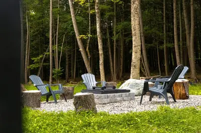 three chairs sitting around a fire pit in the woods at Pur Nature et Spa Owl's Head in Mansonville