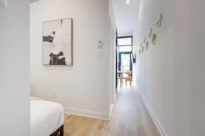 a white room with a bed and a hallway at Le Mile End by M11 - Luxurious & Cozy 1BDR Unit in Montréal