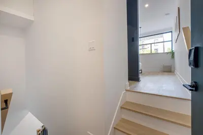 a hallway with white walls and stairs with a mirror at Le Mile End by M11 - 2 BDR Loft with Sofa Bed in Montréal