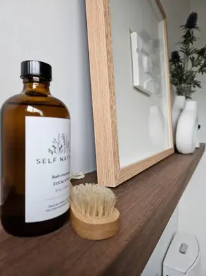 a bottle of oil sitting on a shelf next to a mirror at Chalet Le Hygge Hytte - Ski - Golf - Spa in Thetford Mines