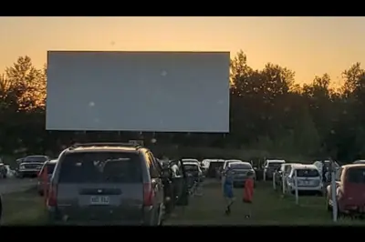 a large screen in a parking lot with cars at Chalet familial et SPA à proximité du Mont Orford in Orford