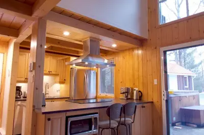 a kitchen with a counter and chairs in a cabin at Chalet familial et SPA à proximité du Mont Orford in Orford