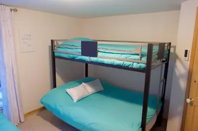 a bedroom with two bunk beds with blue sheets at Chalet familial et SPA à proximité du Mont Orford in Orford