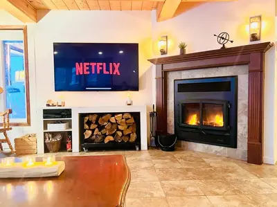 a living room with a television and a fireplace at Chalet familial et SPA à proximité du Mont Orford in Orford