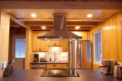 a kitchen with a stainless steel refrigerator and wooden cabinets at Chalet familial et SPA à proximité du Mont Orford in Orford