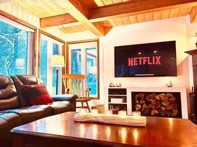 a living room with a couch and a tv above a fireplace at Chalet familial et SPA à proximité du Mont Orford in Orford