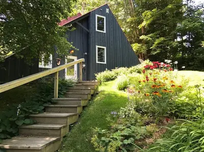 a black shed with stairs leading to a garden at Chalet tout inclus avec SPA près du Mont Orford in Orford