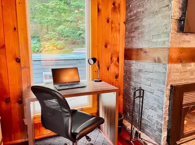 a laptop computer sitting on a desk next to a fireplace at Chalet tout inclus avec SPA près du Mont Orford in Orford