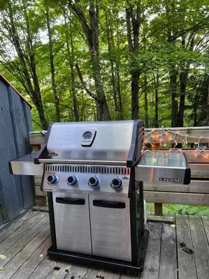 a grill sitting on a deck next to a picnic table at Chalet tout inclus avec SPA près du Mont Orford in Orford