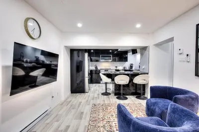 a living room with blue chairs and a kitchen at Le Rêve Montréal! New & Modern! Easy Access Downtown & Attractions! in Montréal