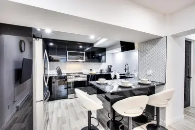 a kitchen with white chairs and a table in a room at Le Rêve Montréal! New & Modern! Easy Access Downtown & Attractions! in Montréal