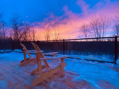 a couple of benches in the snow with a sunset at Pur Nature et Spa Eastman in Eastman