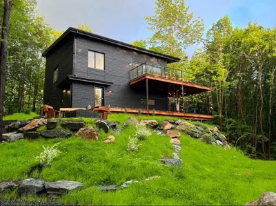 a black house sitting on top of a lush green hill at Pur Nature et Spa Eastman in Eastman