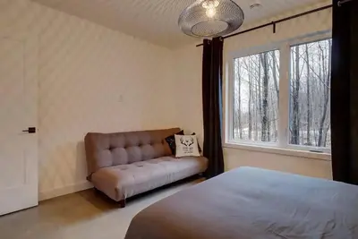 a bedroom with a bed and a couch and a window at Pur Nature et Spa Eastman in Eastman