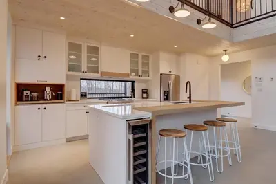 a kitchen with white cabinets and a counter with bar stools at Pur Nature et Spa Eastman in Eastman