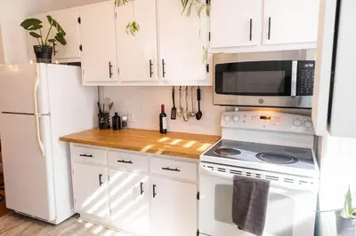 a kitchen with white cabinets and a white refrigerator at Appartement au coeur de Villeray in Montréal