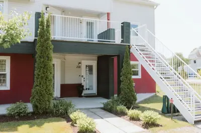 a white and red house with a white staircase at Etoile bleue Beach bike shops Magog-Orford in Magog-Orford