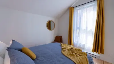 a bedroom with a blue bed and a window at Le Bois Debout - Lake & Trails in Eastman