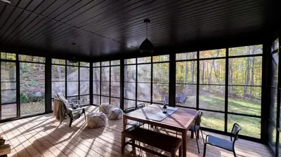 a large screened in porch with a table and chairs at Le Bois Debout - Lake & Trails in Eastman
